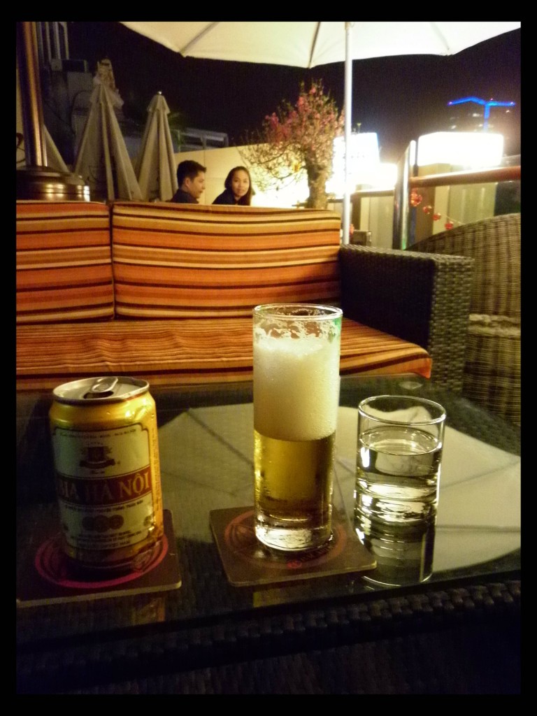 Bia Ha Noi, a pale lager and the most popular brew in the region often as cheap as water.  The ice in my glass has already melted. On the rooftop of "Feel It Cafe" in Hanoi.