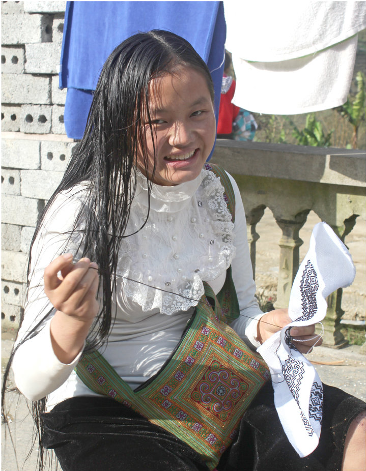 A young woman in Northern Vietnam weaves traditional fabric to sell to tourists in town.  Photo credit: Tom Watt